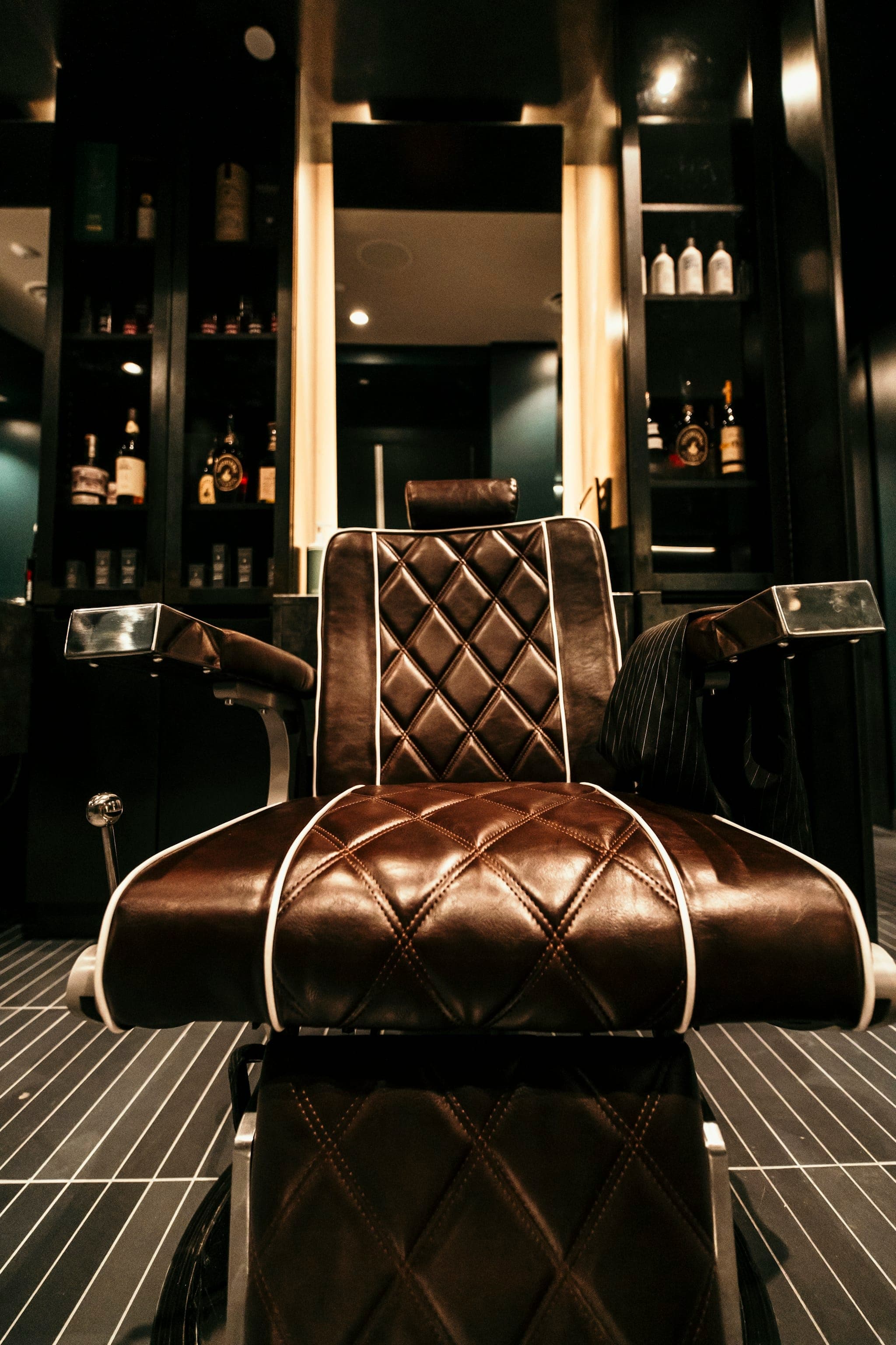 Un fauteuil de barbier vide sous une lumière chaude, prêt pour le prochain client.