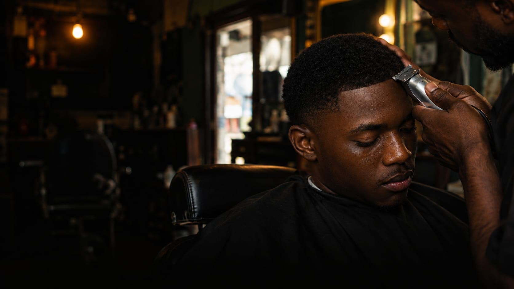 Un barbier trace le contour d'un client à la tondeuse.