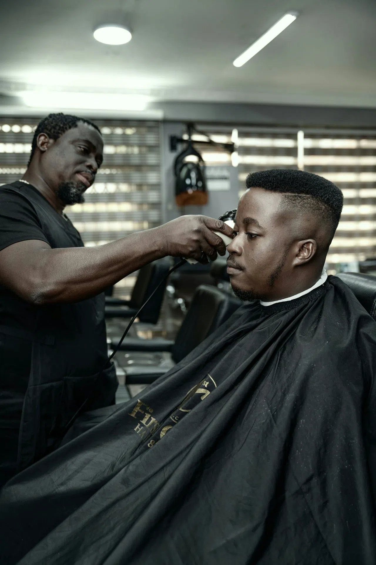 Un barbier trace les contours d'un client dans le fauteuil.